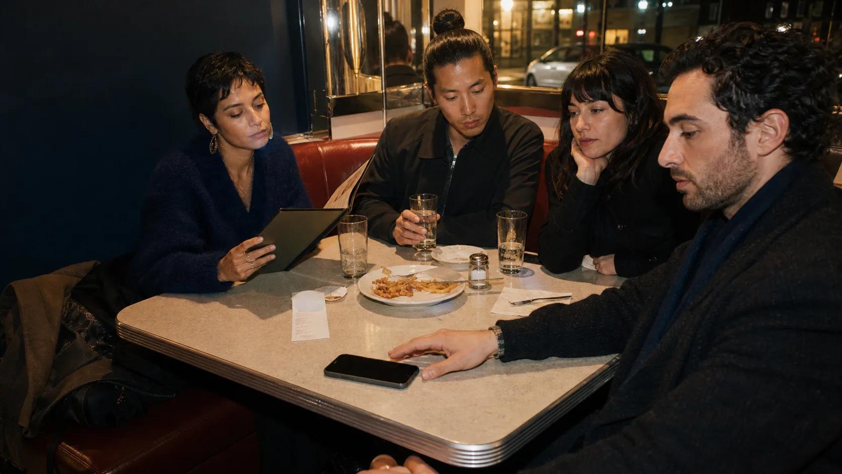 A group at a diner table in the moment after a joke misses.